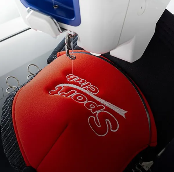 Cagoule rouge personnalisée avec broderie stylisée « Styl’ de Com » sur machine à coudre